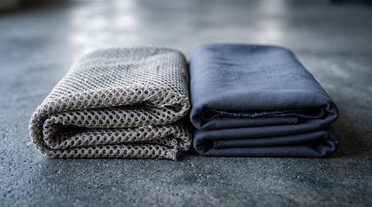 Two folded stacks of plain athletic knit fabric side by side, one lightweight open mesh and one heavy dense knit, lit to show the difference in weave density