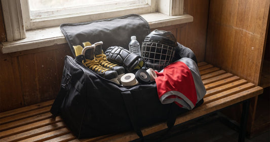 Open beer league hockey bag on a locker room bench packed with skates, gloves, helmet, tape and a red jersey