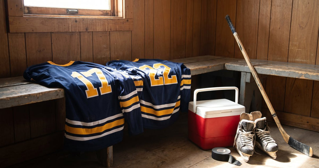 Navy and gold custom beer league hockey jerseys #17 and #22 on a locker room bench with a red cooler and skates