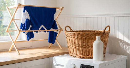 Blue and white custom hockey jersey air drying on a wooden rack in a laundry room beside a basket and detergent