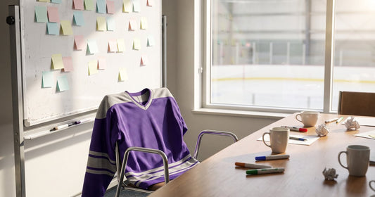 Whiteboard of sticky notes for hockey team name ideas, a purple jersey on a chair and coffee mugs on the table