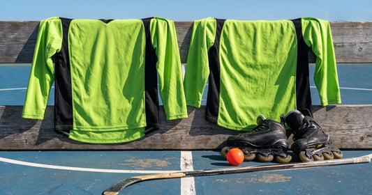 Lime green and black custom roller hockey jerseys draped on outdoor rink boards with inline skates, ball and stick