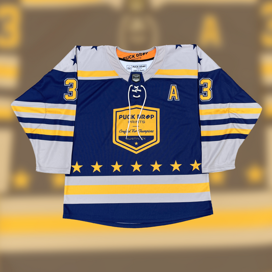 Navy, grey and gold Puck Drop Prints sublimated hockey jersey laid flat with a laced collar