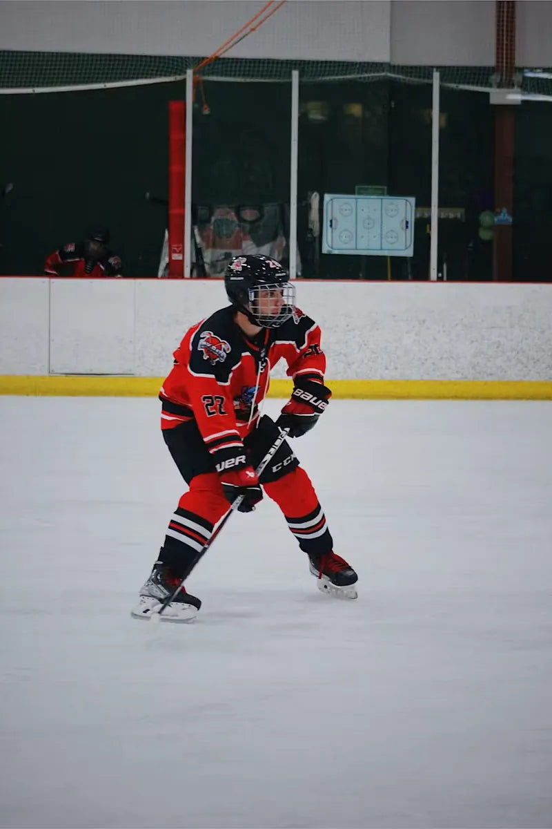 Rink Rats player skating with the puck in a custom orange and black jersey