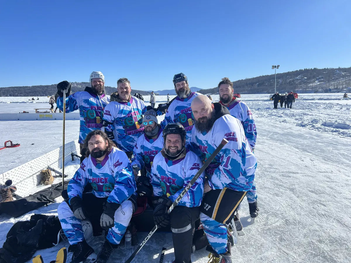 Puck Buddies team in matching blue and purple custom jerseys on a frozen lake