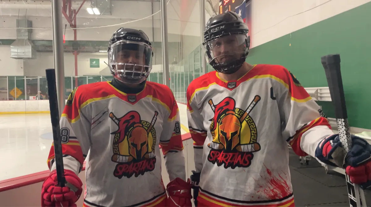 Two Spartans players in white custom jerseys at the rink