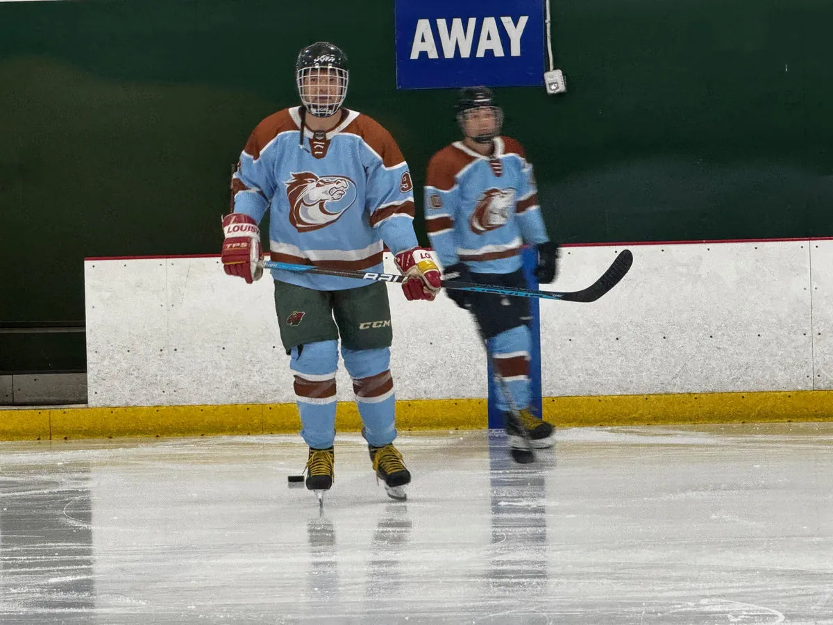 Two Austin Wranglers players standing on the ice by the bench
