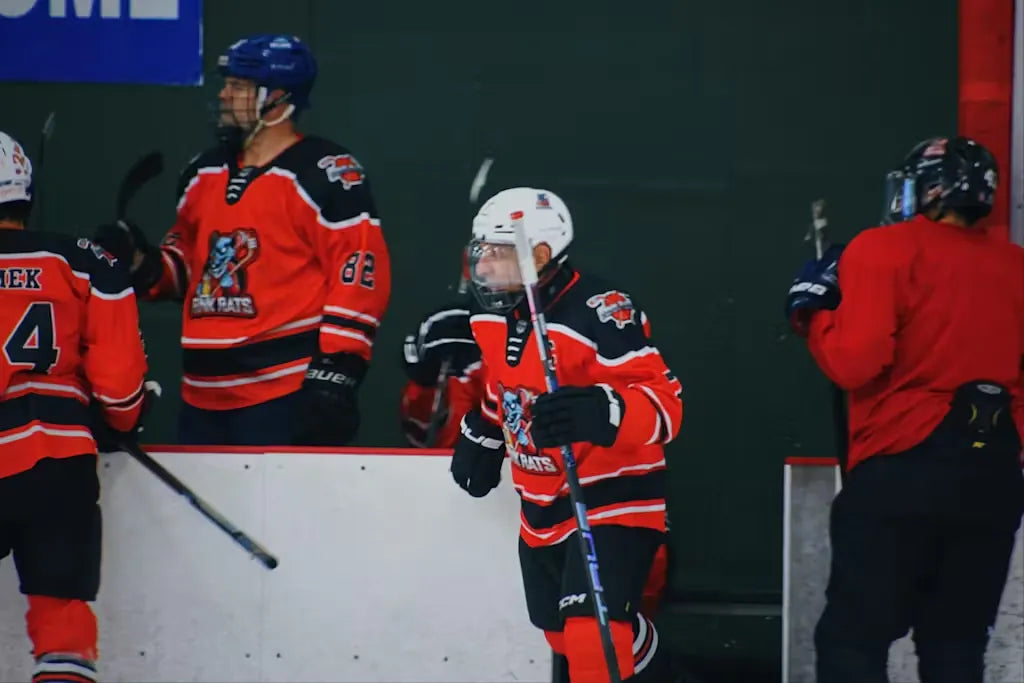 Rink Rats players at the bench in custom orange jerseys